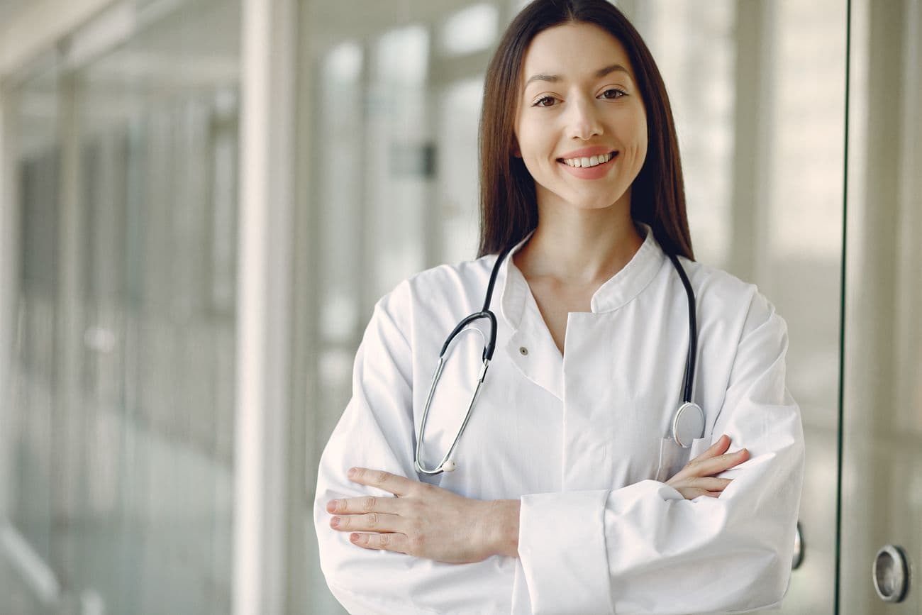 Médica sorrindo no corredor de uma clínica da rede credenciada